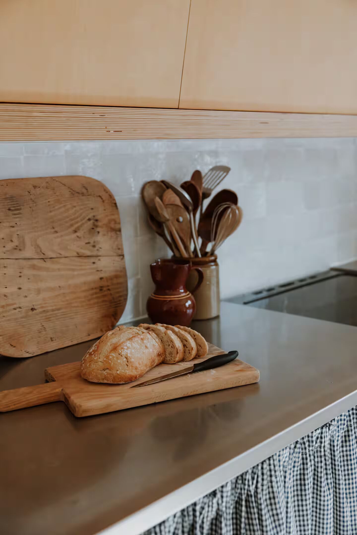 A kitchen counter with a cutting board, a loaf of bread, and a knife.