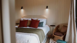Ein Schlafzimmer mit Bett, Kissen, einem Sessel und Nachttischen.