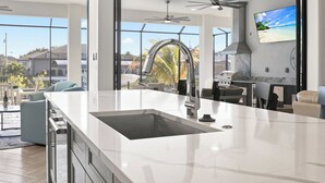 Een moderne keuken met een groot eiland, een inbouwspoelbak en een plafondventilator.