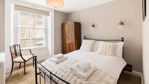 Une chambre à coucher avec un lit, une chaise, une armoire et une fenêtre.