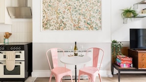 Une cuisine équipée d’une cuisinière, d’un four et d’un coin repas avec des chaises et une table roses.