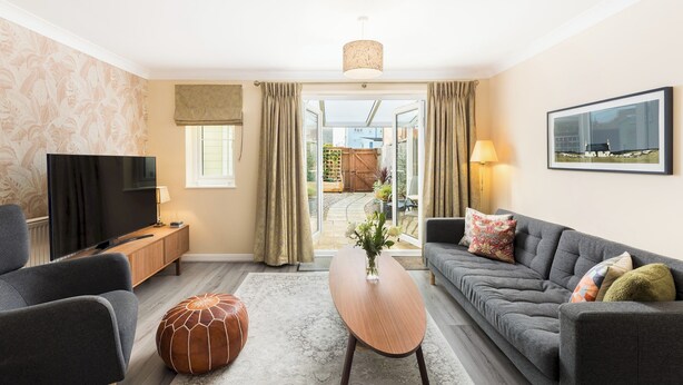 Un salon moderne avec un téléviseur à écran plat, un canapé, une table basse et un pouf.