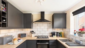Une cuisine moderne avec des meubles de couleur sombre, une cuisinière à gaz, un four encastré et une fenêtre donnant sur l’extérieur.