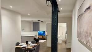 A modern kitchen with a central island, a dining area with a table set for four, and a large abstract painting on the wall. - Converted Ancoats Mill - Walk to Victoria - Pass the Keys (Manchester)