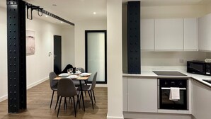 A modern kitchen with white cabinets, a black microwave, and a built-in oven. - Converted Ancoats Mill - Walk to Victoria - Pass the Keys (Manchester)