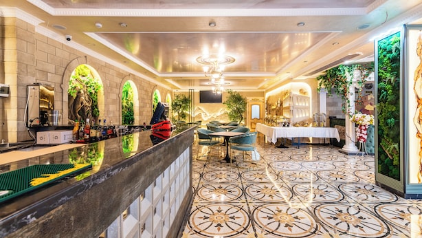 Un hall d’hôtel doté d’un sol en marbre, d’un comptoir de réception et d’un espace détente avec des tables et des chaises.