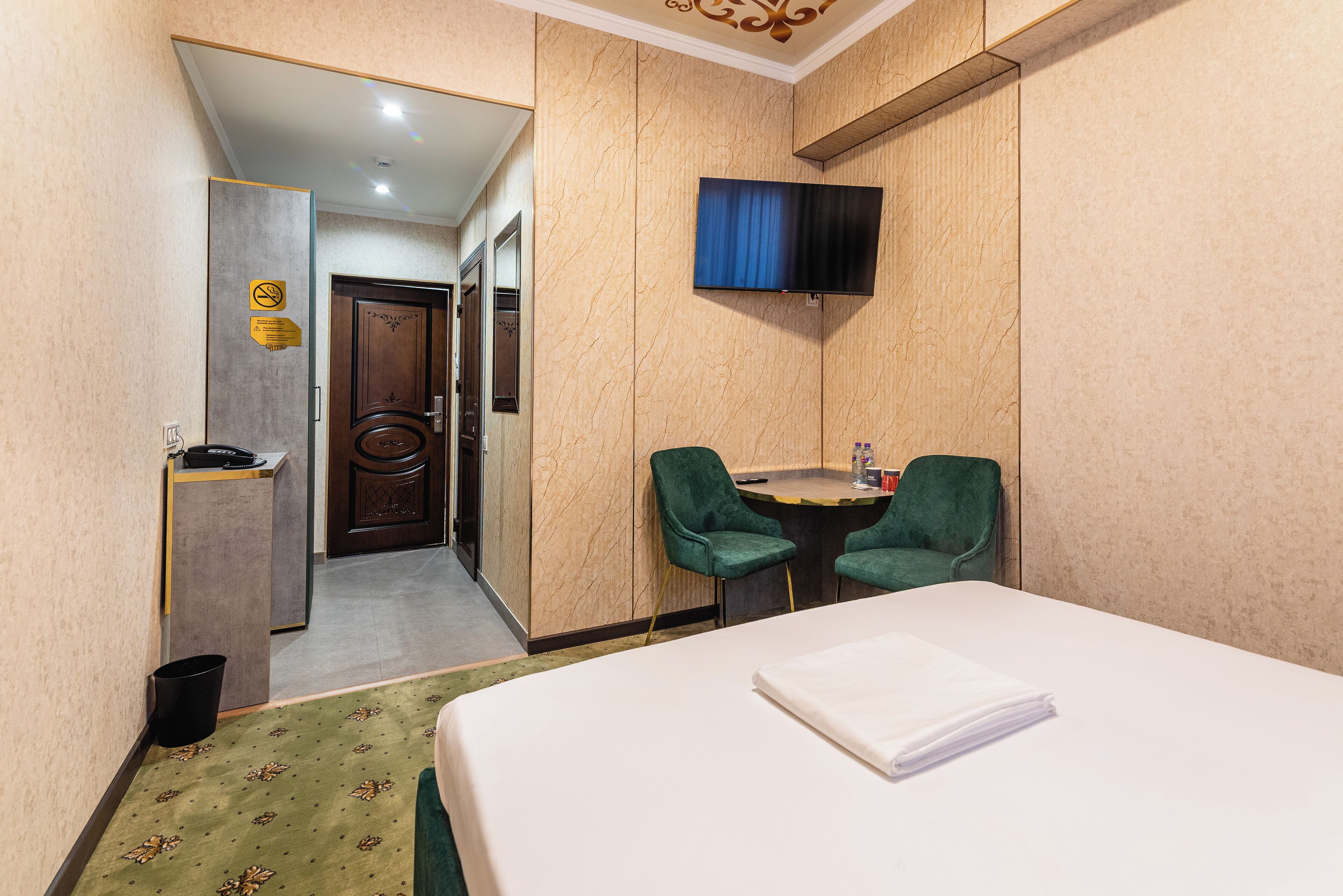 A hotel room with a bed, a desk with a chair, a television, and a bathroom door.