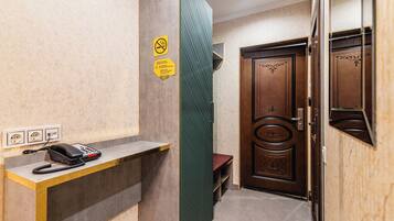 Un área de recepción con teléfono, un banco y una puerta con panel decorativo.