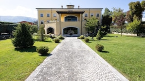 A two-story building with a central entrance, surrounded by well-maintained lawns and hedges. - Hotel La Dimora del Baco (L'Aquila)