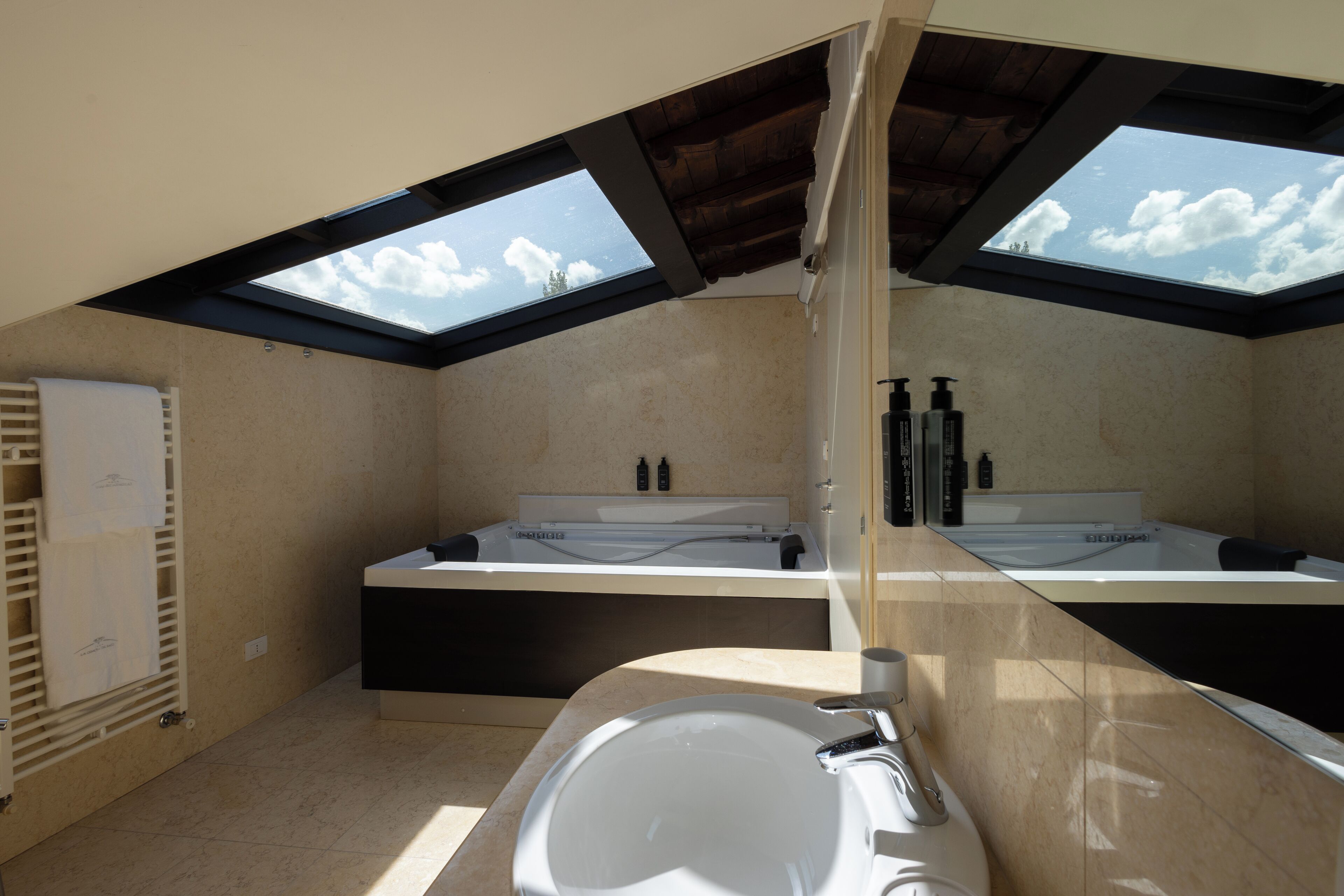 A modern bathroom with skylights, a large bathtub, and a separate shower area.