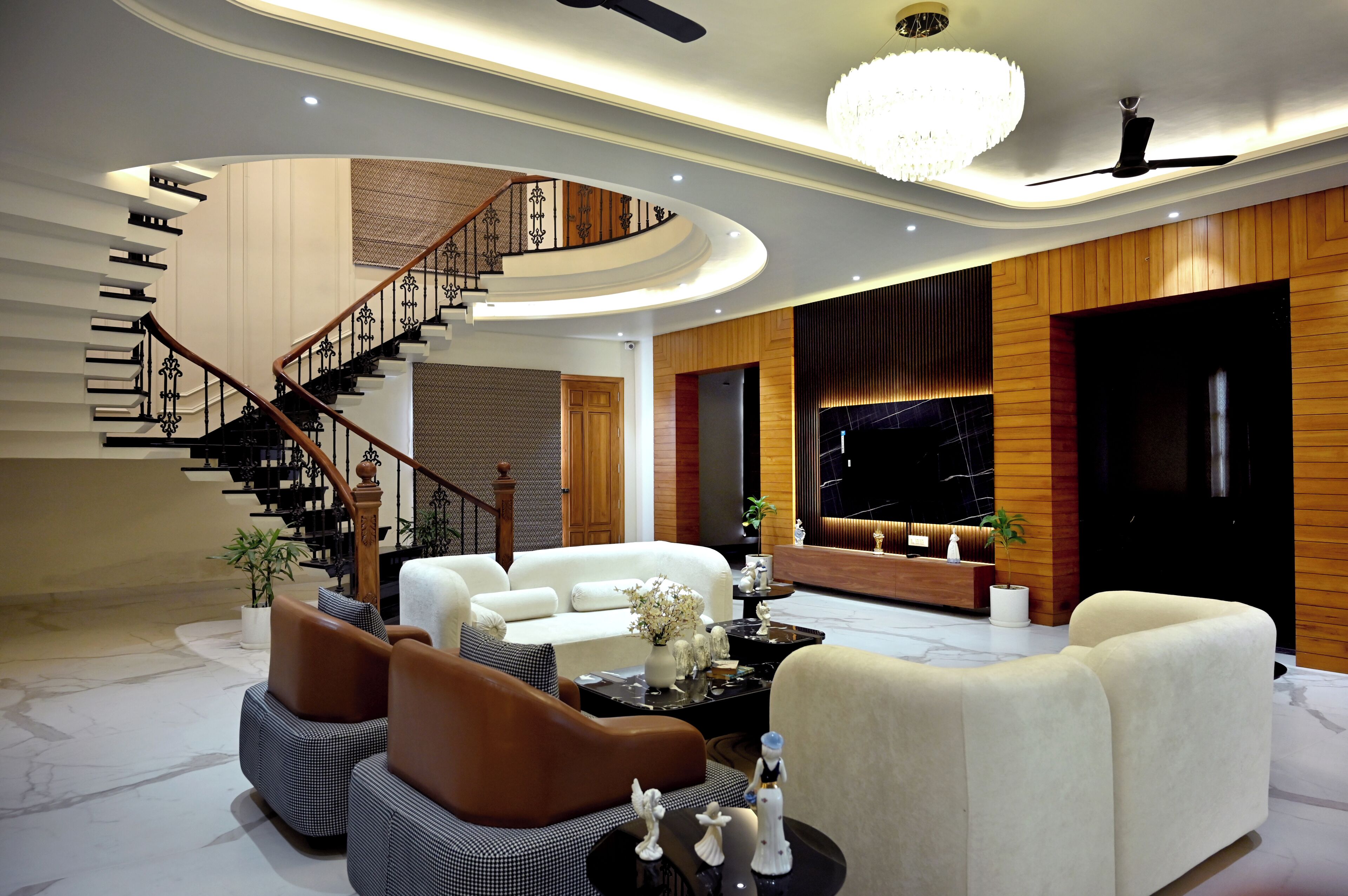 Amplia sala de estar con una escalera curva, un gran candelabro y una recepción.