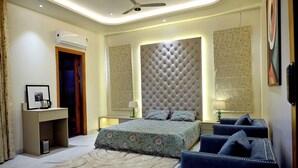A bedroom with a large bed, a desk, a chair, and a ceiling fan. - Florentino The Luxury Villa (Amritsar)