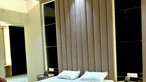 A modern bedroom with a large bed, a ceiling fan, and a nightstand with a lamp. - Florentino The Luxury Villa (Amritsar)