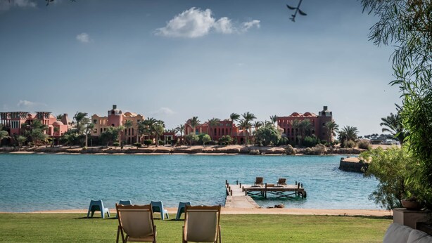 A view of a waterfront property with a pool, lounge chairs, and a dock extending into the water. - Beit El Mona Sanctuary (Sea & Beach Front) (Hurghada)