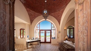 An interior with a high arched doorway, a chandelier, a table with items, and a bed with a view. - Beit El Mona Sanctuary (Sea & Beach Front) (Hurghada)