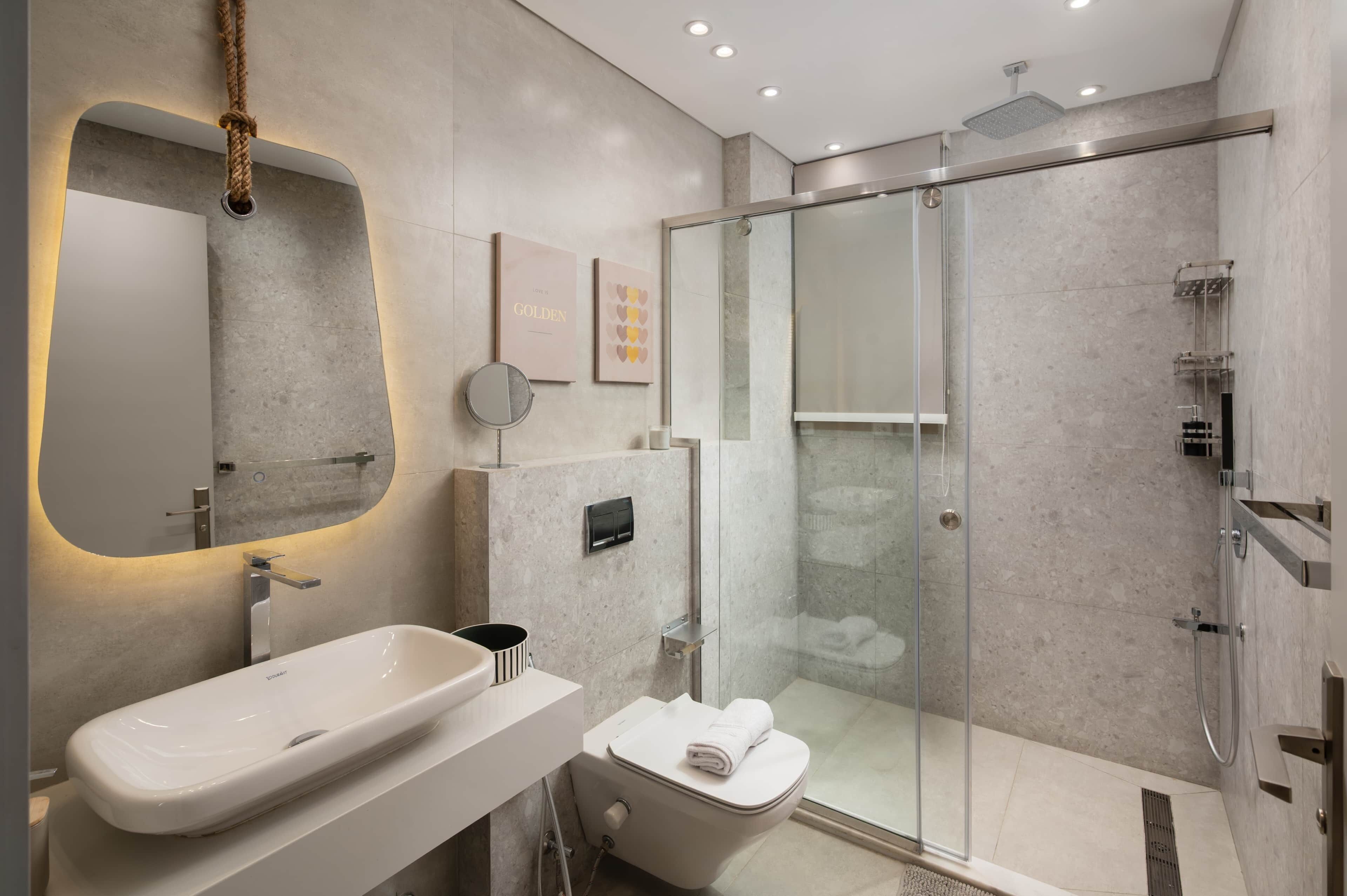 Une salle de bain moderne avec un grand lavabo, des toilettes et une douche à parois de verre.