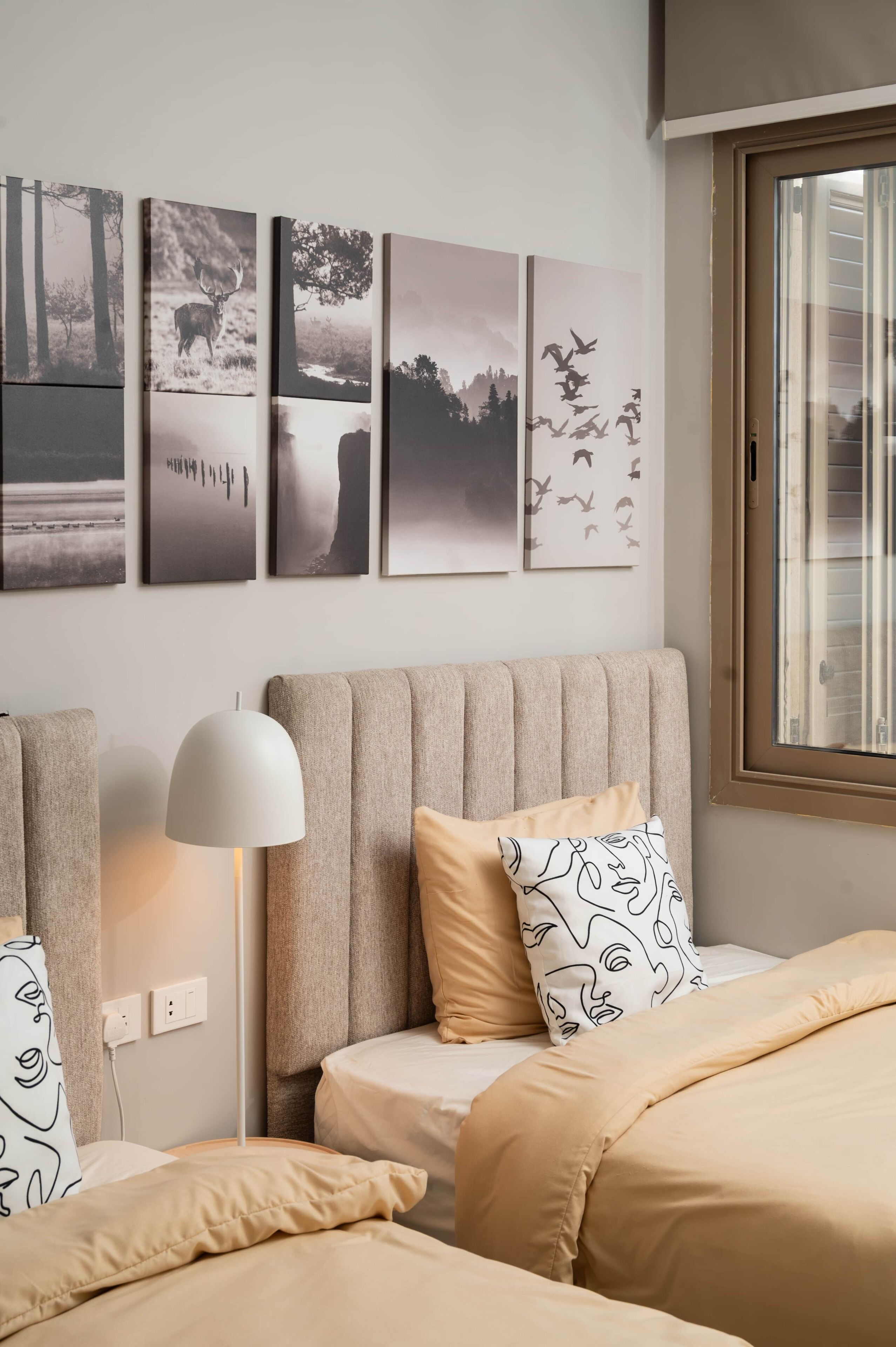 Una camera d'albergo con un letto, una lampada e opere d'arte alle pareti.