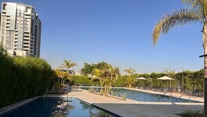 Ein Schwimmbecken mit klar blauem Wasser, umgeben von Grünpflanzen und Palmen.