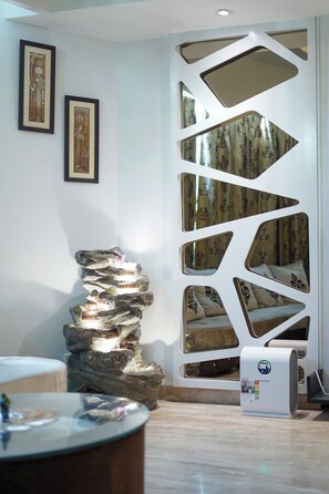 A modern interior with a unique wall design, a decorative rock structure, and a small table with a lamp.
