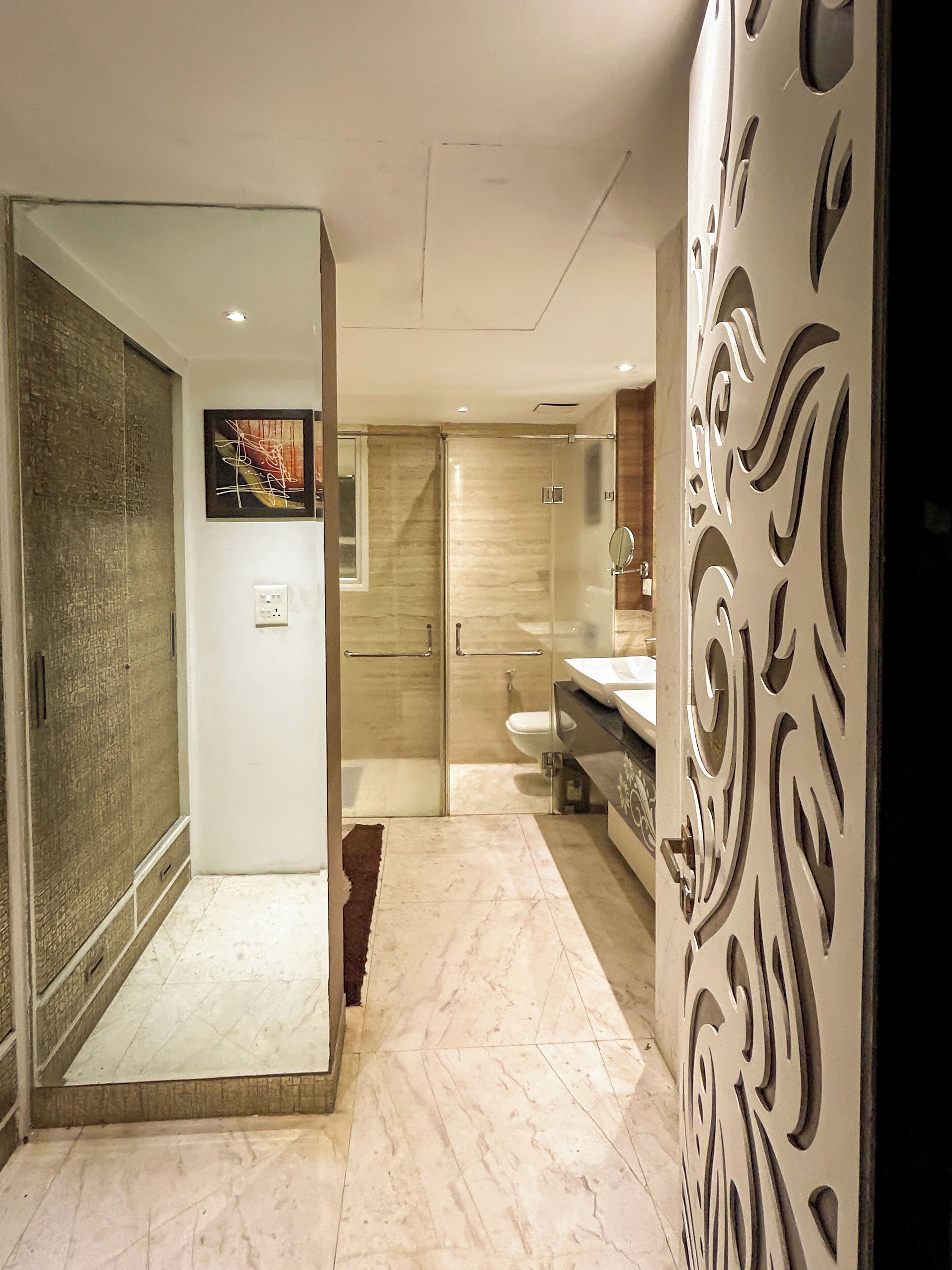 A modern bathroom with a glass shower enclosure, a marble floor, and a decorative panel.