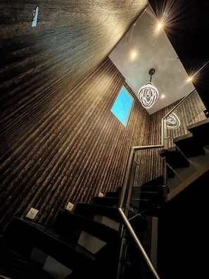 A modern interior with a wooden wall, a staircase, and a ceiling light fixture.