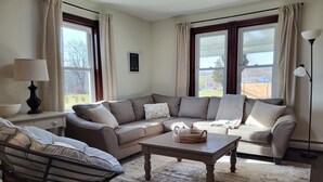 Ein Wohnzimmer mit einer Couch, einem Couchtisch, einer Lampe und einem Fenster mit Vorhängen.