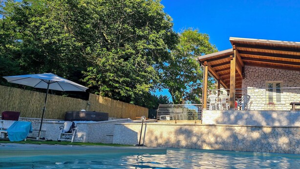 A poolside area with a covered seating area, stone walls, and a clear blue sky. - Secret Garden (Grottolella)