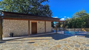 A stone building with a wooden door and a covered patio area. - Secret Garden (Grottolella)