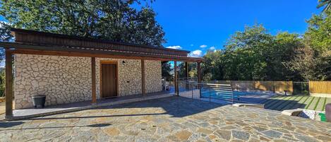 Un edificio de piedra con puerta de madera y un patio cubierto.