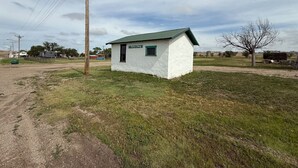 A small, single-story building with a green roof and a sign that reads "City Jail." - Grasshopper Flats RV Pad (Interior)