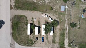 An aerial view of a campground with RVs and tents, a dirt road, and a small building. - Grasshopper Flats RV Pad (Interior)