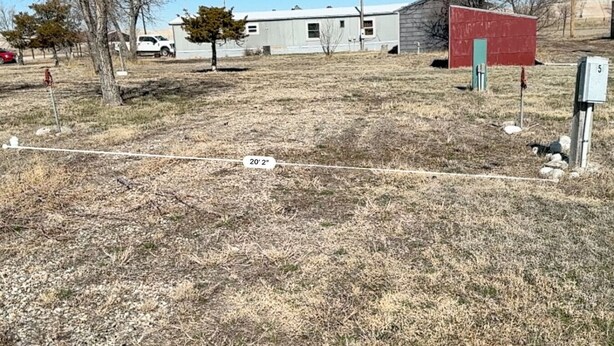A fenced area with a utility box marked '5' and a red shed. - Grasshopper Flats RV Pad (Interior)