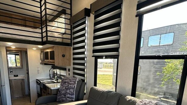 Un intérieur de camping-car moderne comprenant un coin cuisine, un canapé et un escalier menant à un niveau supérieur.