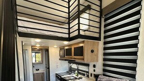 Un intérieur de camping-car compact comprenant un coin cuisine, un espace repas et un salon avec un canapé.