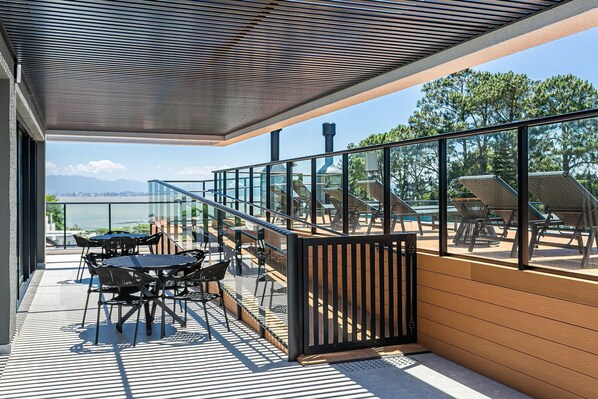 A balcony with outdoor furniture, a view of the sea, and a wooden deck.