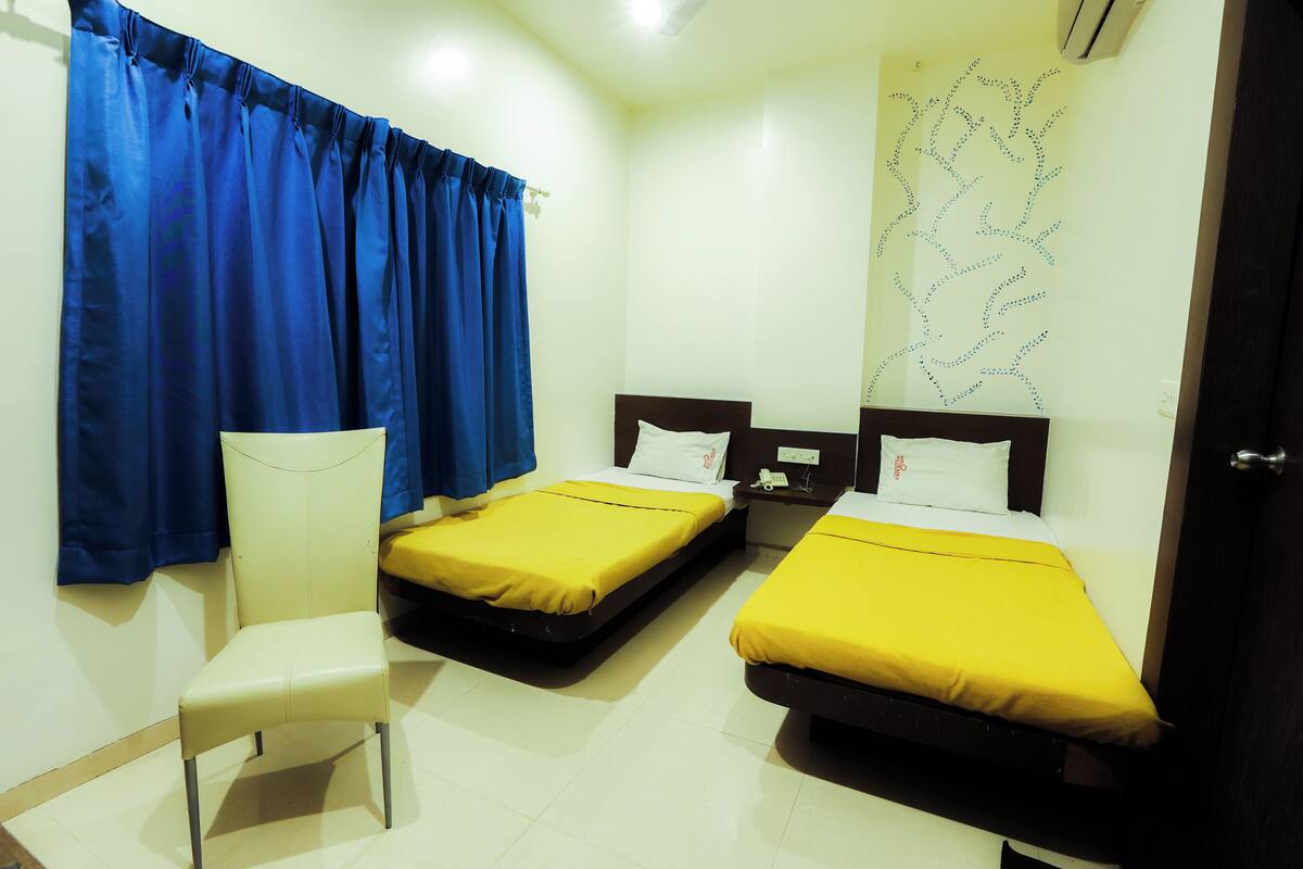 A hotel room with two beds, a chair, and a map on the wall.