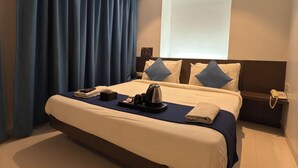 Ein modernes Hotelzimmer mit einem großen Bett, einem Flachbildfernseher und einem Telefon auf dem Nachttisch.