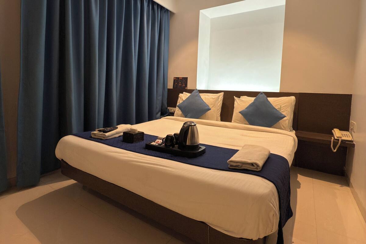 A modern hotel room with a large bed, a flat-screen TV, and a telephone on the nightstand.