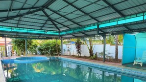 A covered swimming pool with a tiled floor and a metal roof structure. - Invito Beach Resort – A Bright, Beautiful Arabian Sea Stay (Kannur)