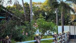 A paved walkway with a decorative fence and palm trees. - Invito Beach Resort – A Bright, Beautiful Arabian Sea Stay (Kannur)