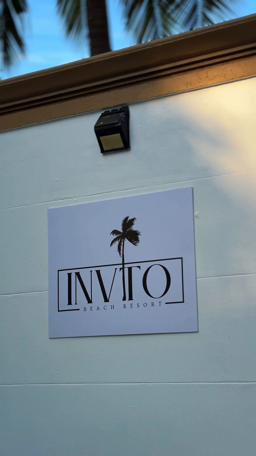 A sign for 'Invito Beach Resort' with a palm tree logo.