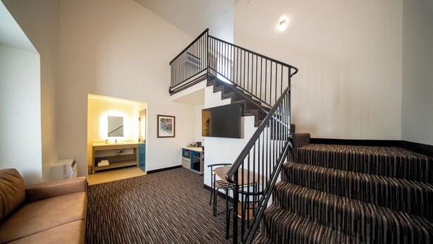 A modern living room with a staircase, a sofa, and a small dining area. - Lemon Heights Inn (Tustin)