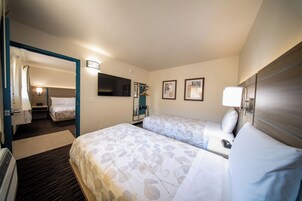 Una habitación de hotel con dos camas, televisor, escritorio y espejo.