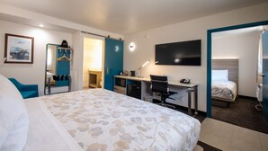 A hotel room with a large bed, a desk with a chair, a TV, and a separate sleeping area. - Lemon Heights Inn (Tustin)