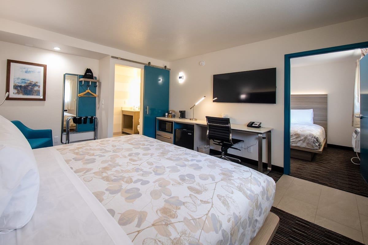 Une chambre d’hôtel dotée d’un grand lit, d’un bureau avec une chaise, d’une télévision et d’un espace nuit séparé.