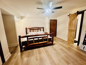 A bedroom with a wooden bed frame, a ceiling fan, and a wooden door. - Wildenmänn- Helen alpine village cozy cabin (Helen)