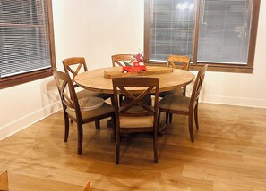 A round wooden dining table with six chairs, a small red toy train, and a decorative item on the table. - Wildenmänn- Helen alpine village cozy cabin (Helen)
