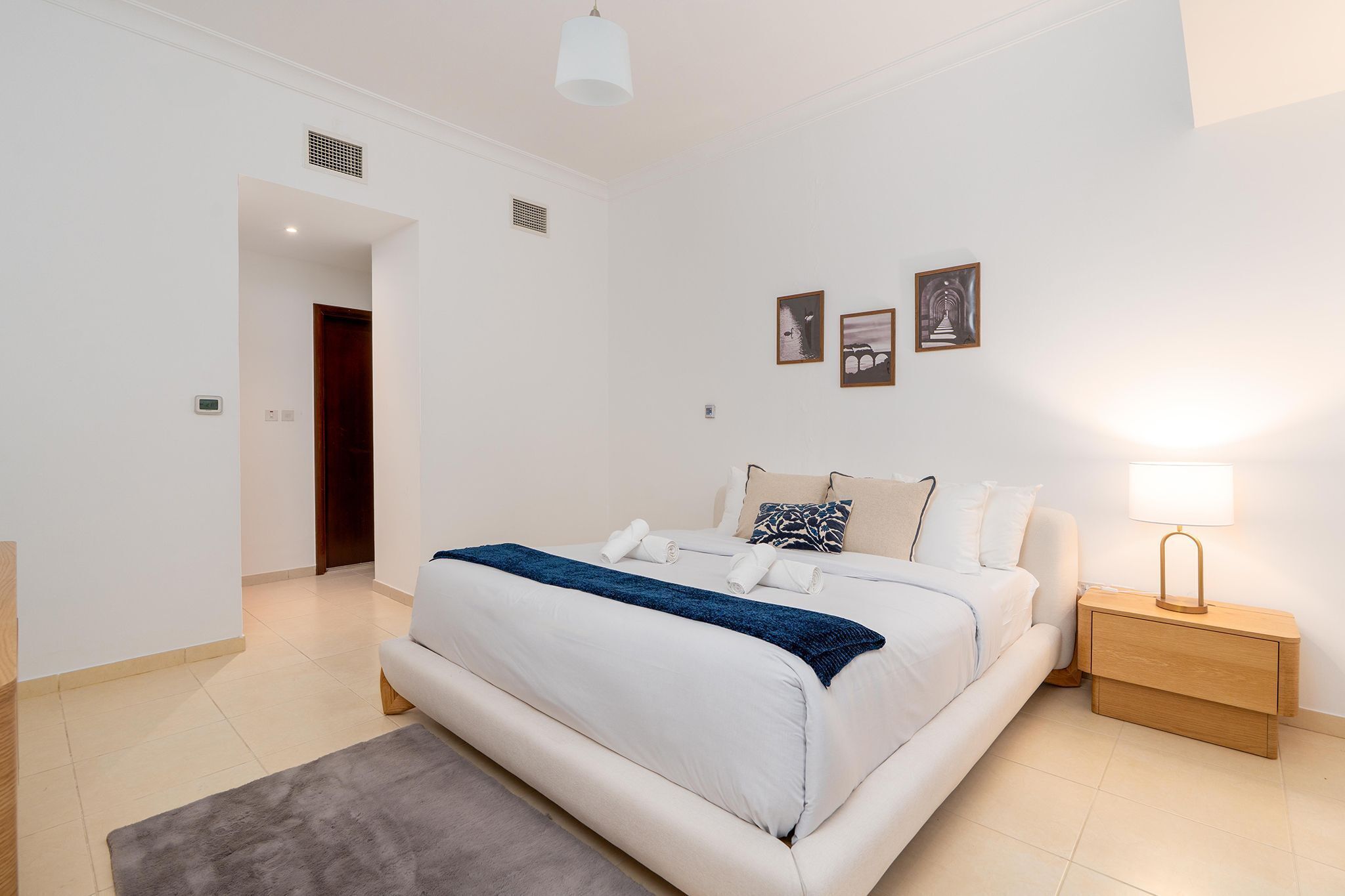 A bedroom with a bed, bedside table, and wall-mounted artwork.