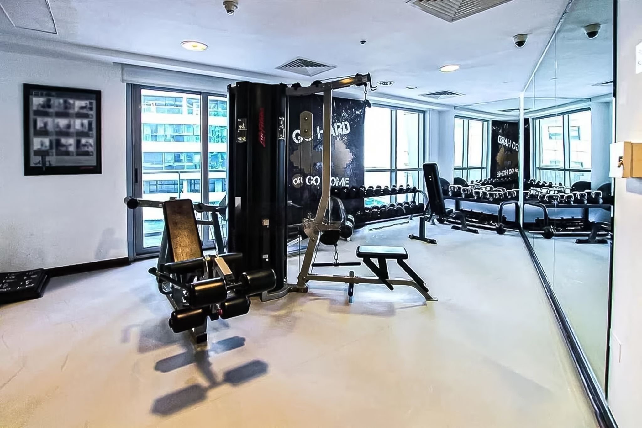 Een sportschool met gewichthefapparatuur, een bank en halters.