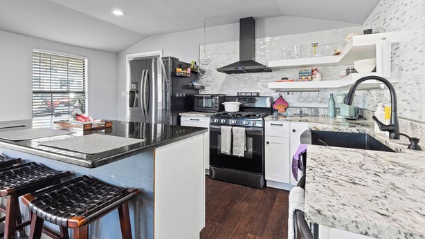 A modern kitchen with a central island, stainless steel appliances, and a black range hood. - Spacious 4-bedroom house in welcoming San Antonio near trails, Pearl, Gardens (San Antonio)